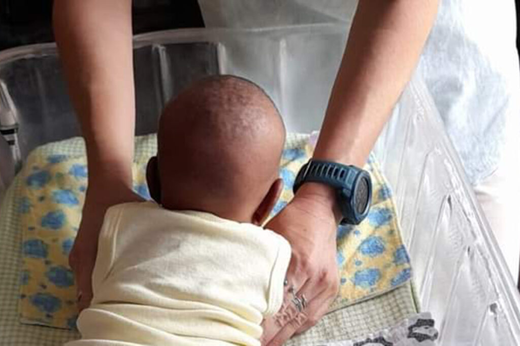 Baby Hope House baby in bed with caregiver